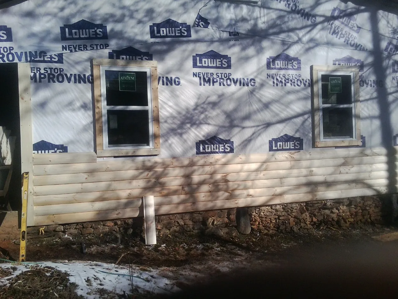 House wrap and new log siding going up on an exterior wall in Huntsville