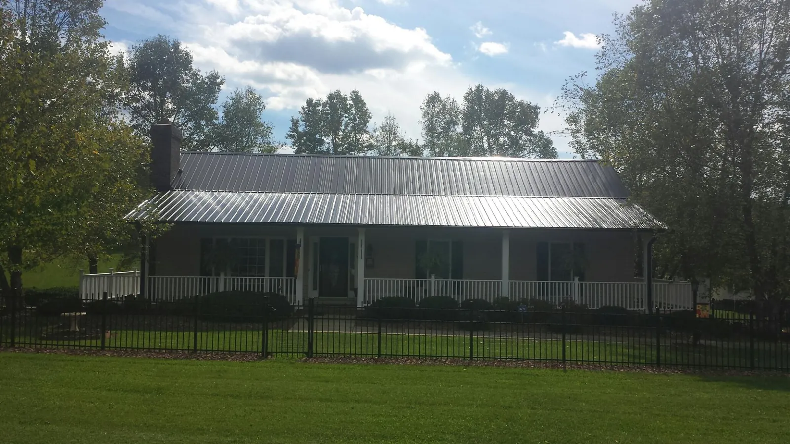 Gray metal roof on a brick ranch with a full width front porch — Gutter Guard Installation work by our crew in Huntsville