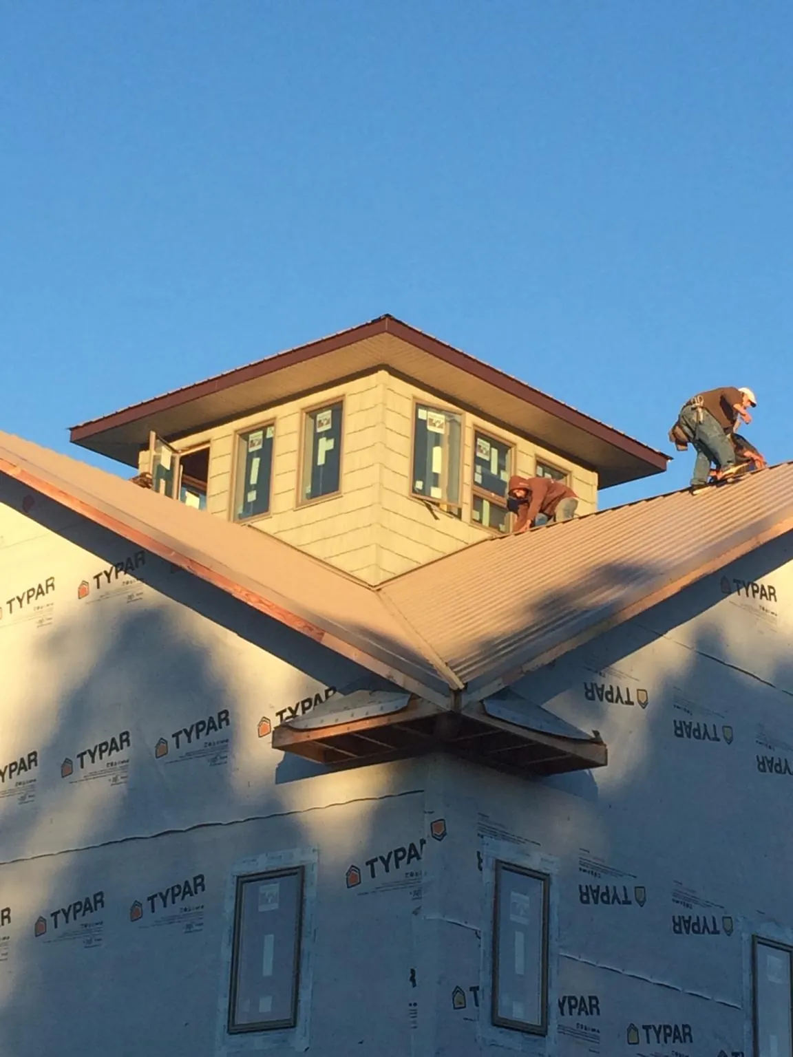 Roofers working around a rooftop cupola on a new metal roof at sunset — Roof Waterproofing in Huntsville by Roofing Brothers